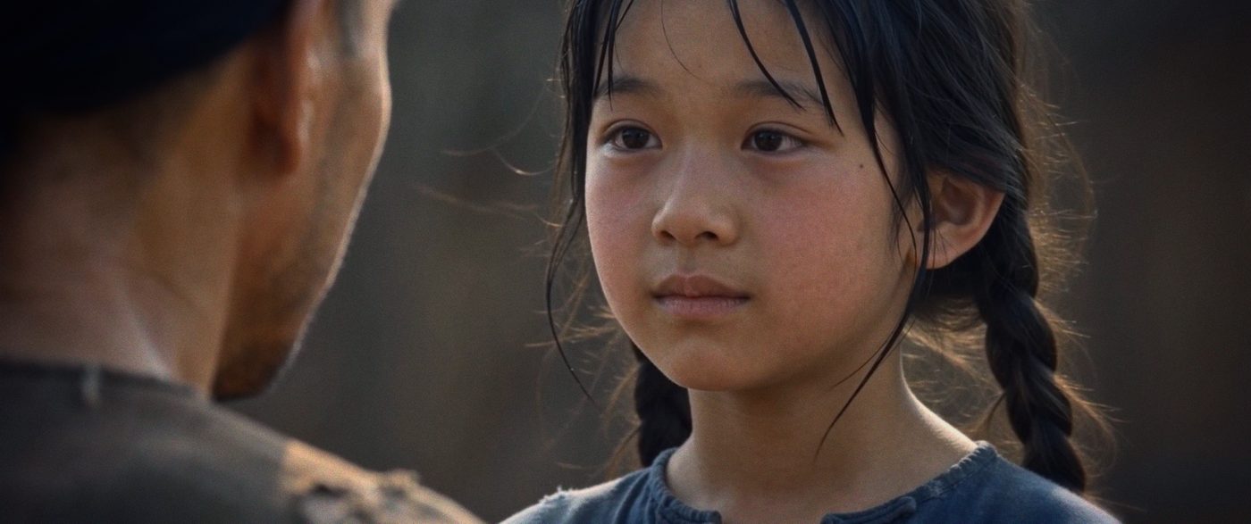 A young girl with braided hair looks up at her father.
